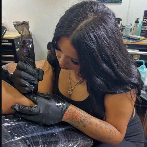 Tattoo artist working on a client's arm.