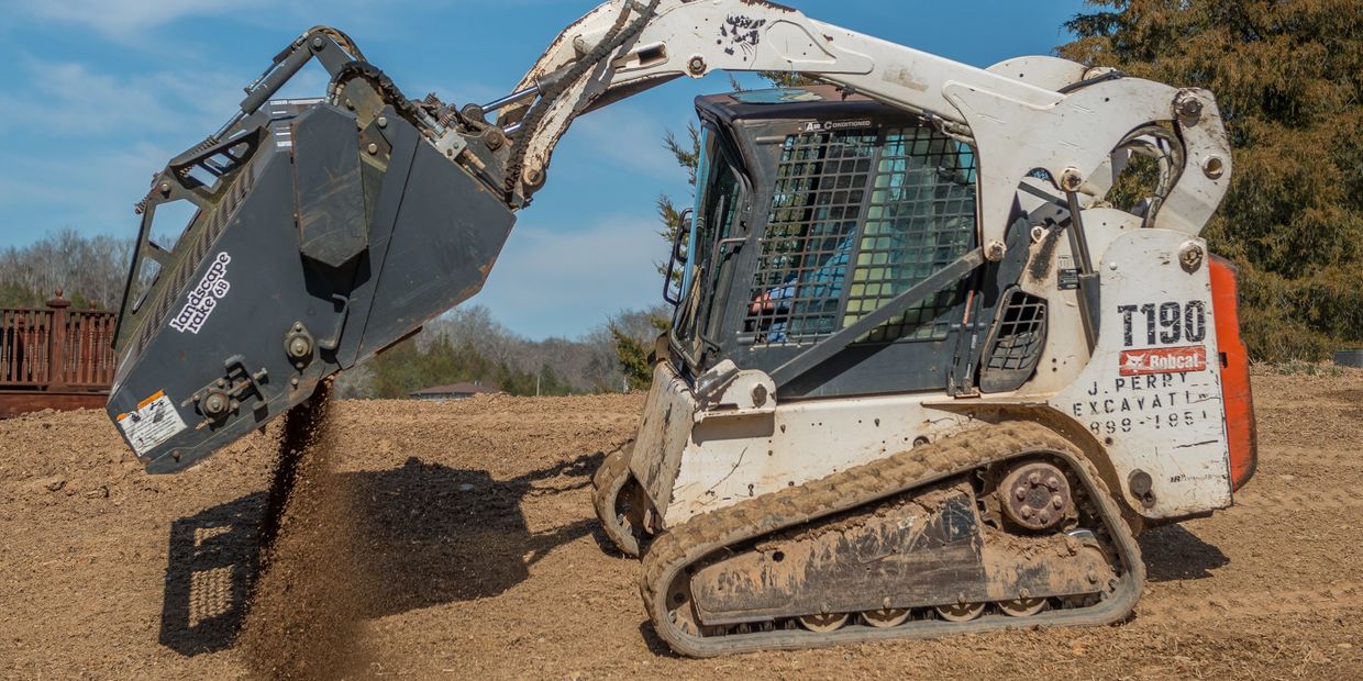 Excavator dumping dirt on a construction site under a clear blue sky.