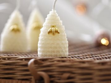 Decorative white candles shaped like beehives with golden bee ornaments.