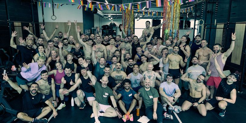 Large group of men posing in a gym with festive decorations.