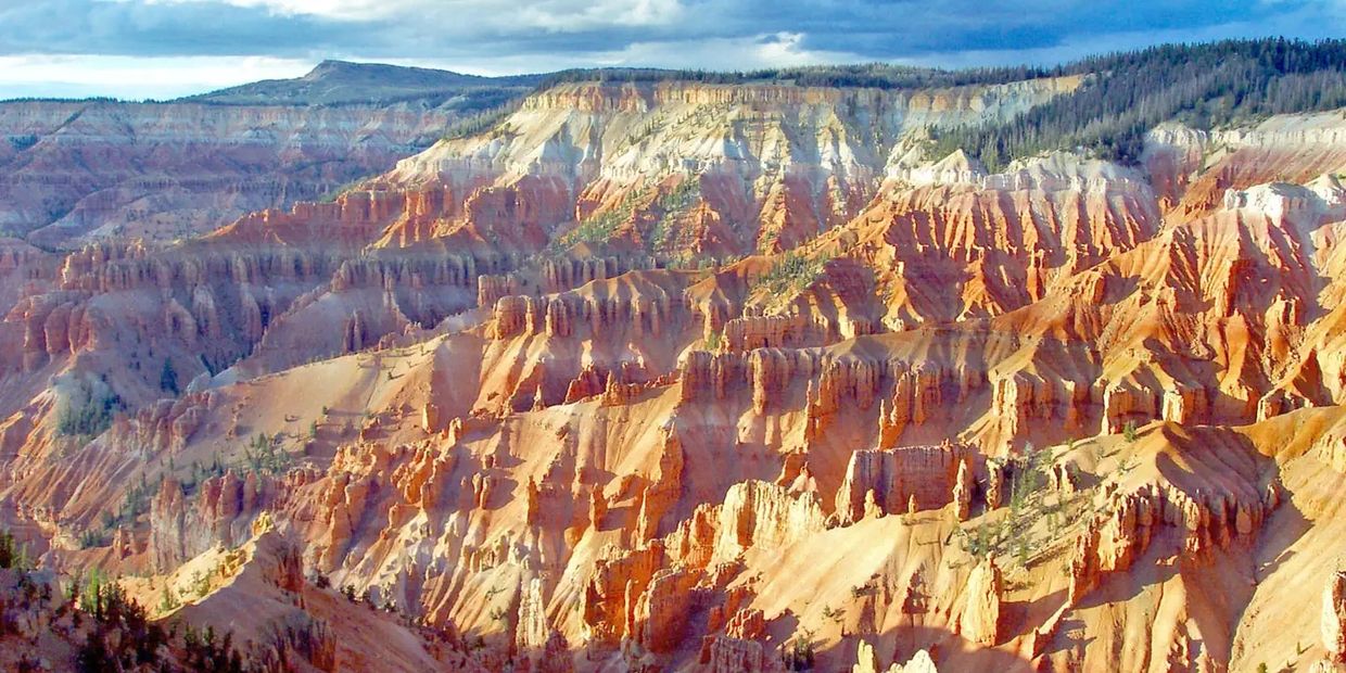 Vibrant orange and white cliffs with intricate rock formations under a cloudy sky.