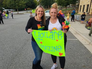 Two women holding a sign that says 'You are amazing'.