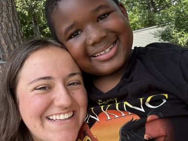 Two people smiling closely together outdoors.