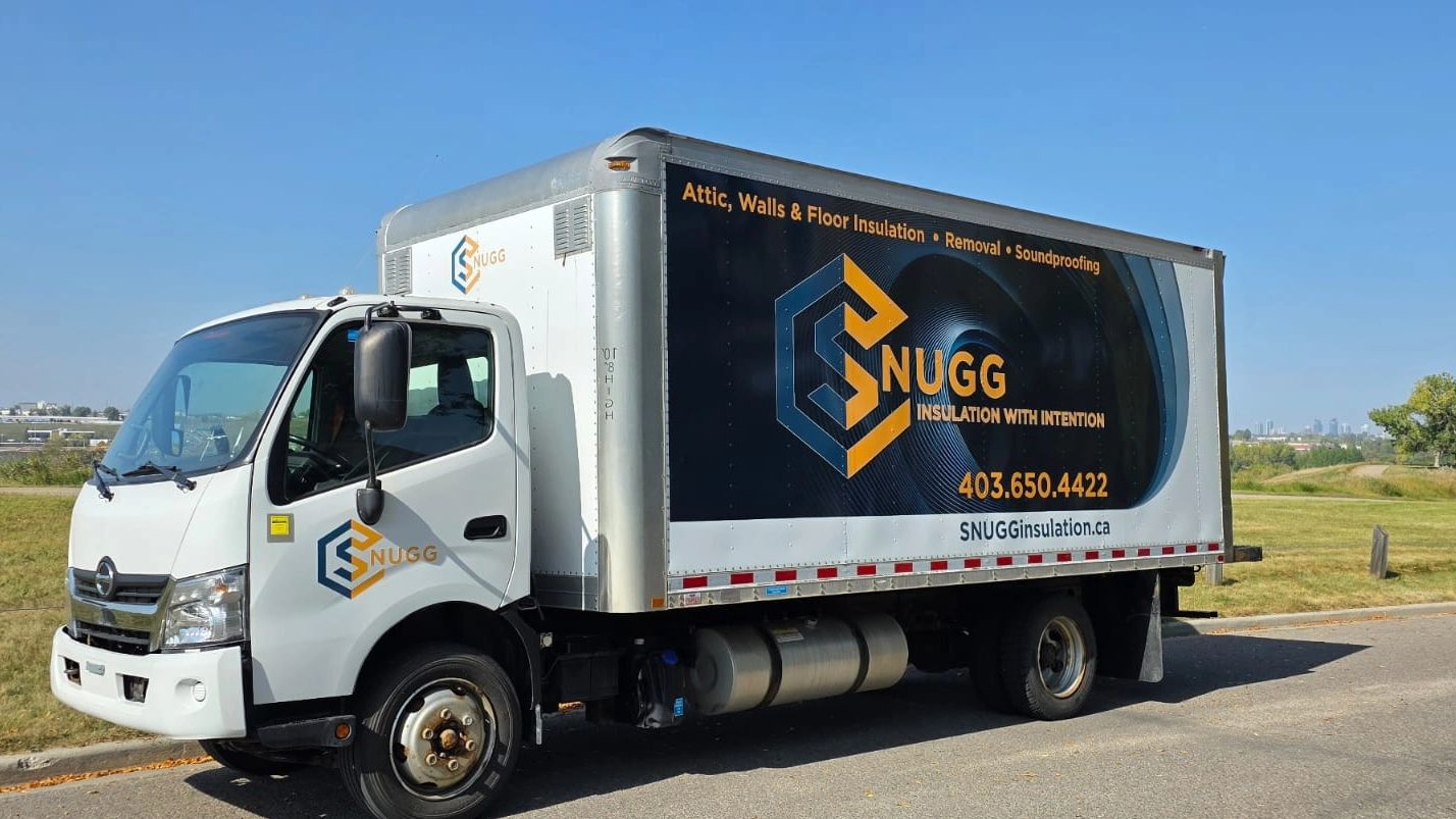 White SNUGG insulation service truck parked on a road under clear skies.