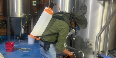 Persona con equipo de protección limpia un tanque industrial.
