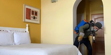 Persona con equipo fumigador desinfectando una habitación.