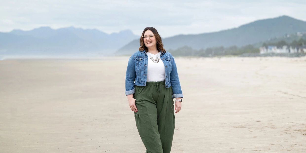 Kristin Van Sickle, vocal teacher and performer in Portland, OR smiling and walking an Oregon beach.