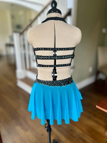 Back view of a blue and black dress with rhinestones on a dress form.