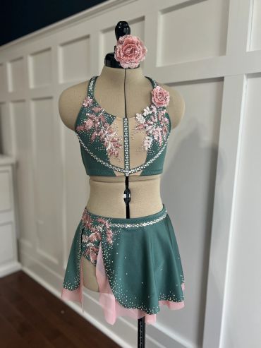 Green and pink embellished dance costume on a dress form.