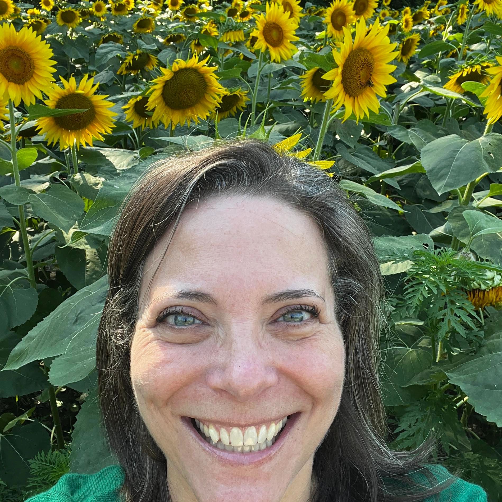 Amy smiling in a field of sunflowers