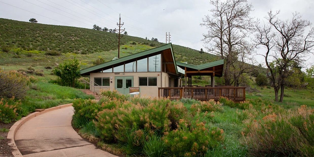 Modern building with green roof in a lush, hilly landscape under a cloudy sky.