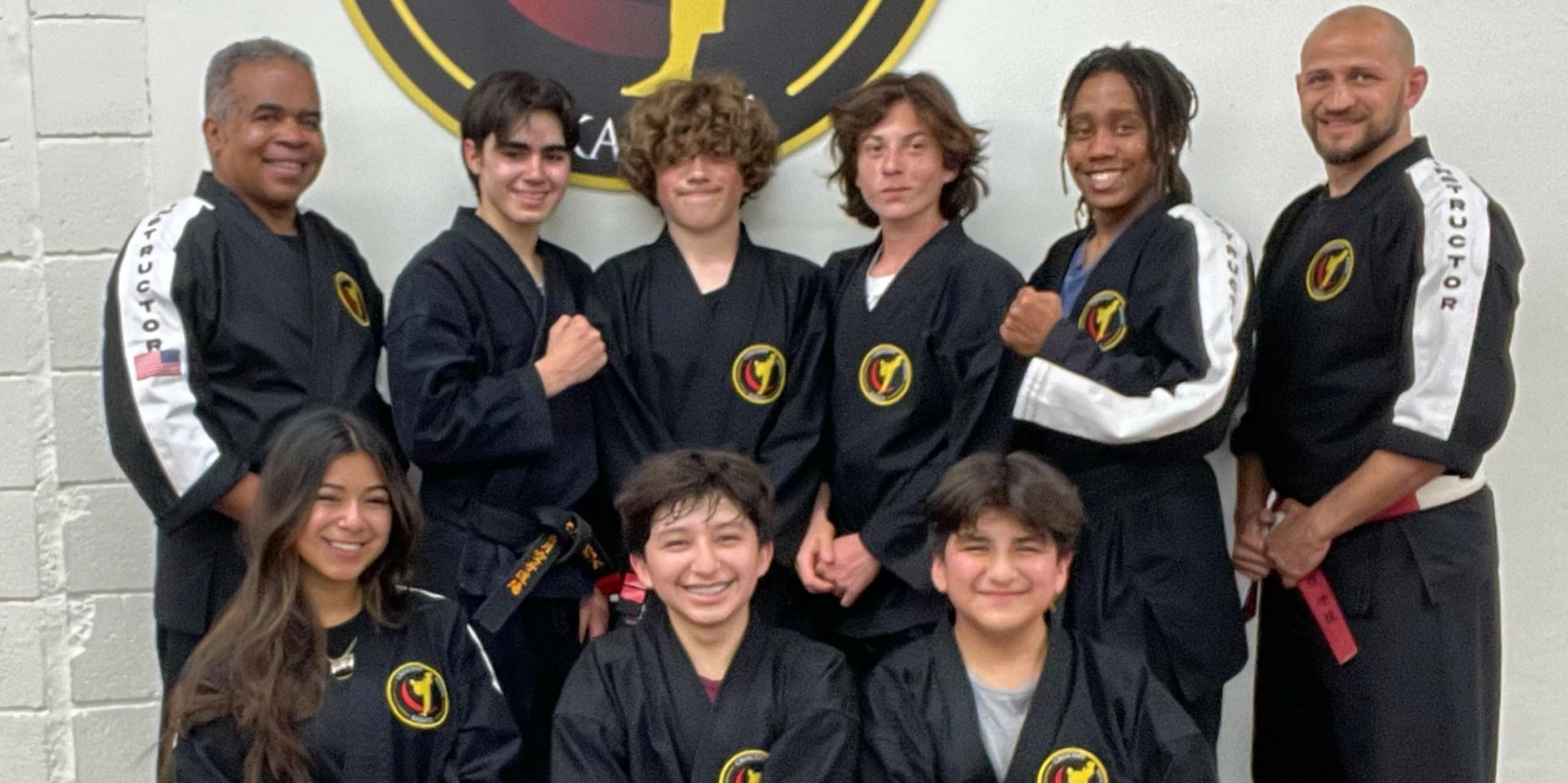 A martial arts group posing in black uniforms on a mat.