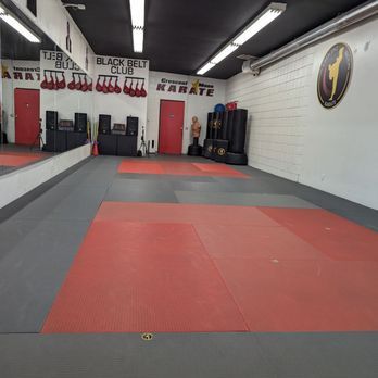 Karate training area with mats and punching bags inside a martial arts gym.