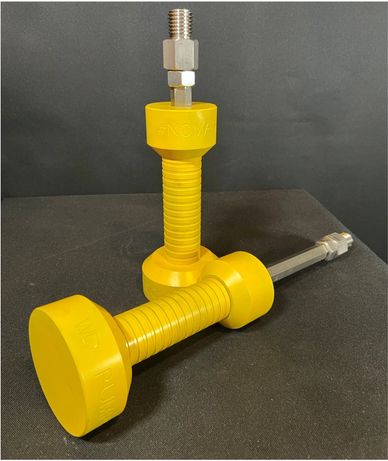 Two yellow mechanical tools with metal fittings on a black surface.