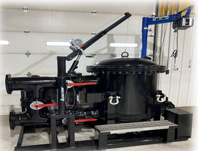 Industrial black machinery with pipes and valves in a workshop.