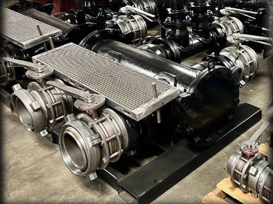 Industrial pump system with multiple connected pipes and valves on a workshop floor.