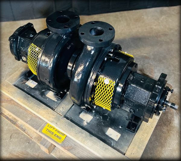 Industrial black pump with yellow safety mesh on wooden pallet.