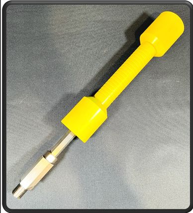 Yellow-handled tool with a metal threaded end on a gray surface.