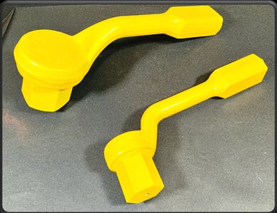 Two yellow plastic tools with hexagonal ends on a dark surface.