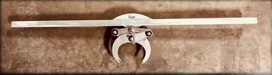 Vintage metal tool with claw-like hooks on a wooden surface.