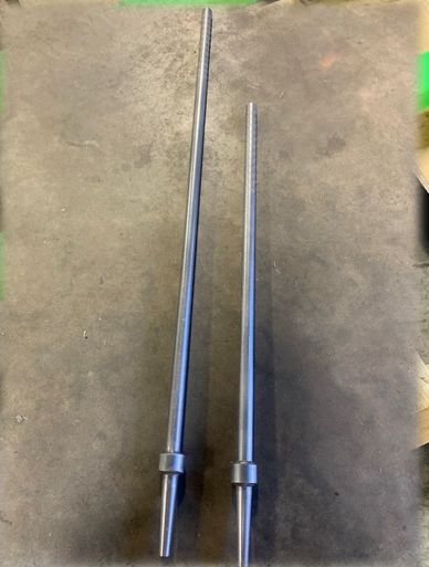 Two long, tapered metal rods placed side by side on a concrete floor.