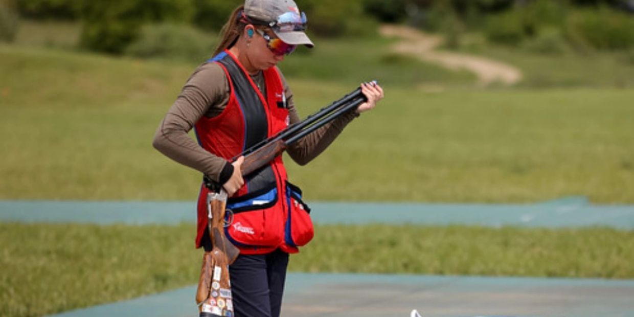 A woman preparing a shotgun outdoors.