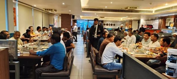 Busy restaurant with patrons dining and waiter serving.