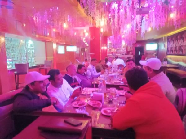 Group of people dining in a restaurant with pink lighting.
