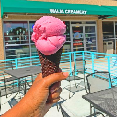 Chocolate waffle cone with strawberry ice cream held in front of the outdoor dining area