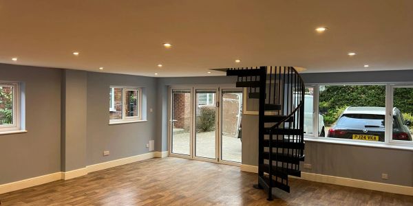Empty room with wooden floor and spiral staircase.