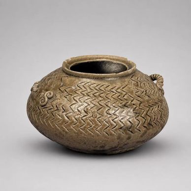 Ancient round pottery vessel with zigzag patterns and small handles.