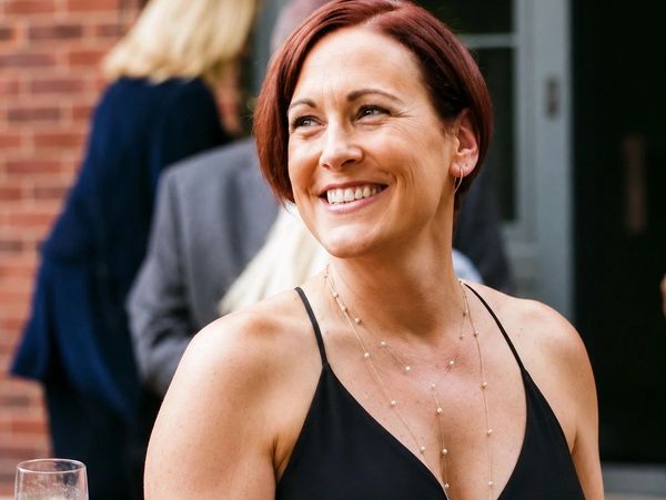 A smiling woman in a black dress at an event.
