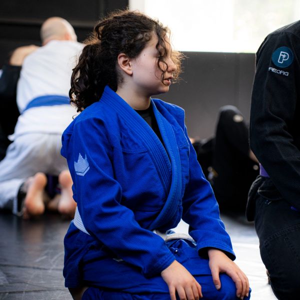 Young girl in blue martial arts gi kneeling