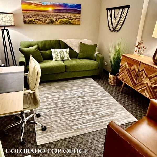 Cozy office with green sofa, wooden desk, and modern decor.