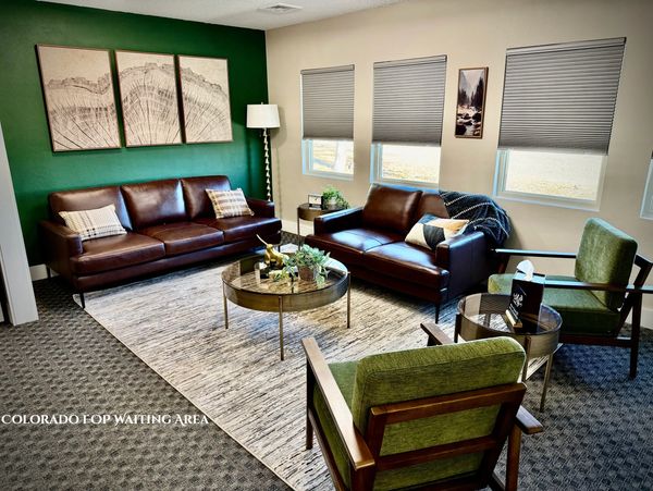 Cozy waiting area with leather sofas and green chairs.