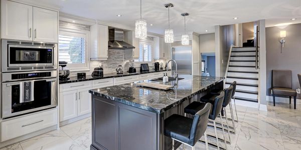 A beautiful, light kitchen with large island. There are chairs at the island. 