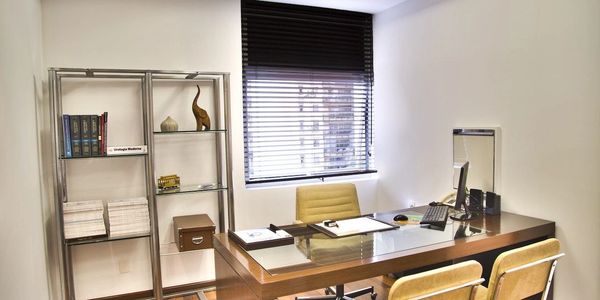 A clean, modern office space with a desk, window and shelf decorated in a minimal fashion.