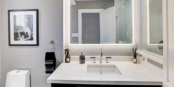 A white bathroom vanity with large, lighted mirror. 