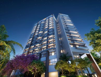Modern high-rise residential building illuminated at night with surrounding greenery.