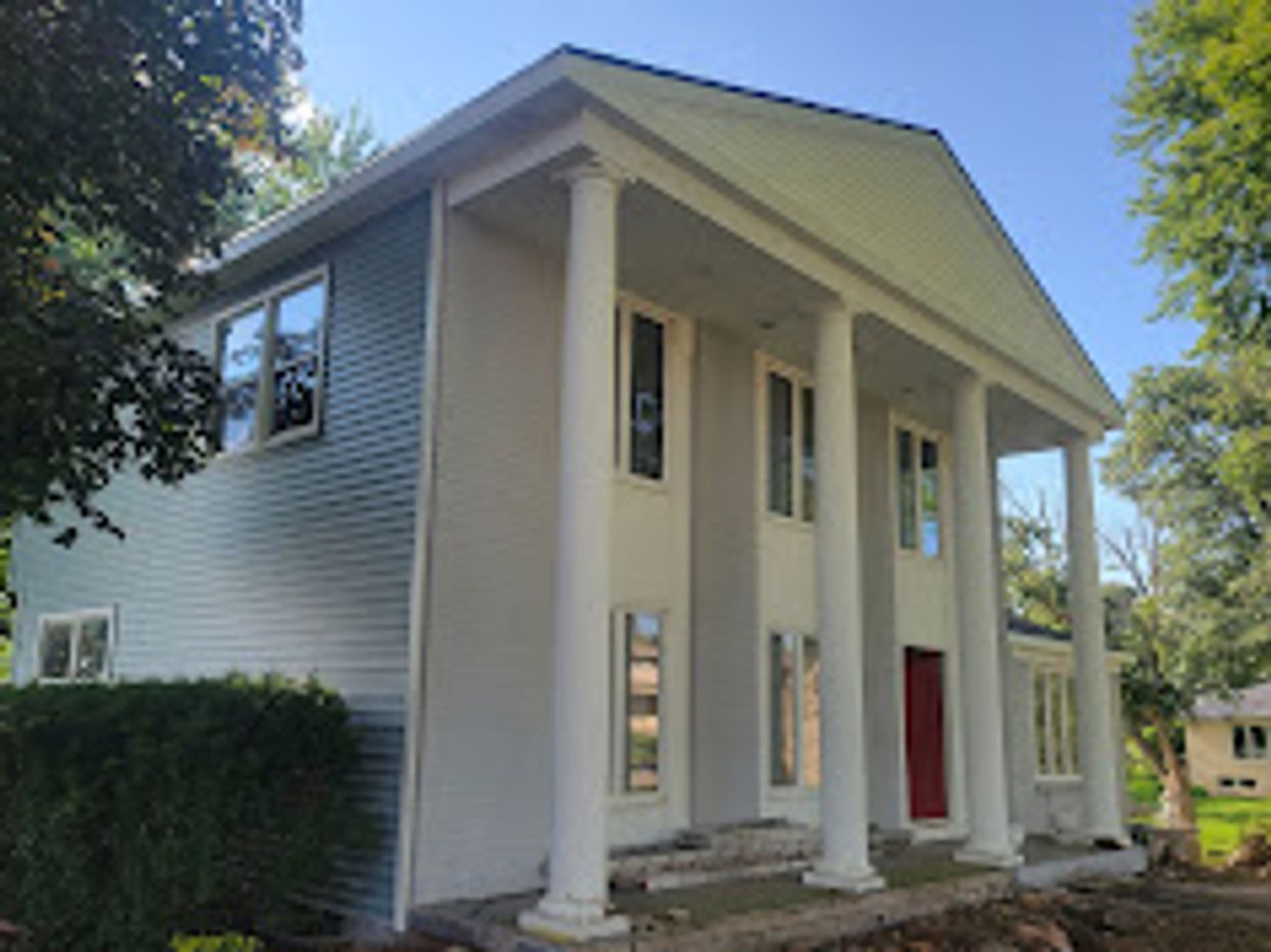 White house with large columns and red door.