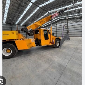 Yellow industrial crane inside a large warehouse lifting a metal platform.