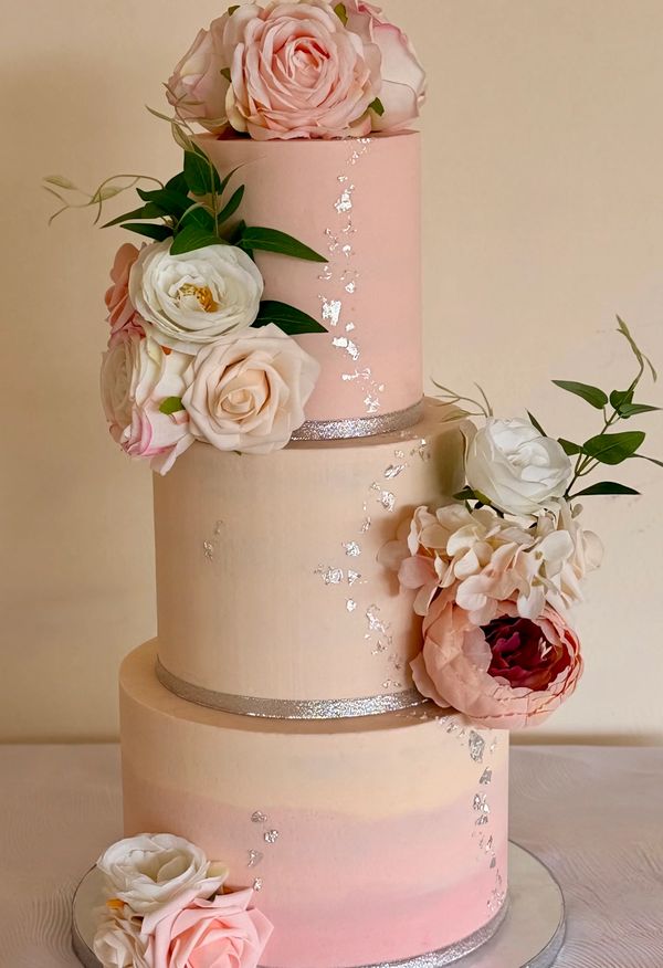 Pretty 3 tier buttercream wedding cake in shades of pastel ombre pink with silver leaf