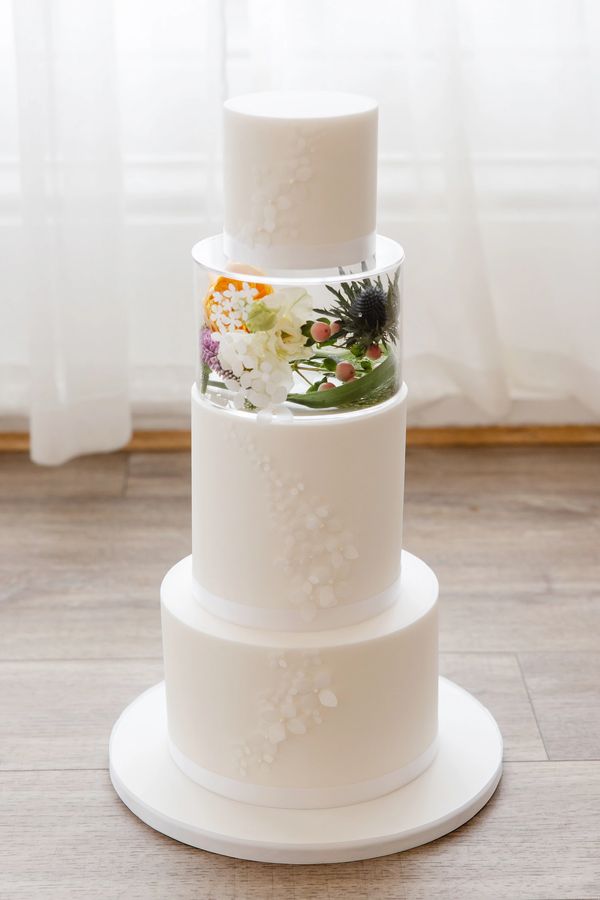 3 tier white fondant wedding cake with delicate wafer paper flowers and a clear perspex tier