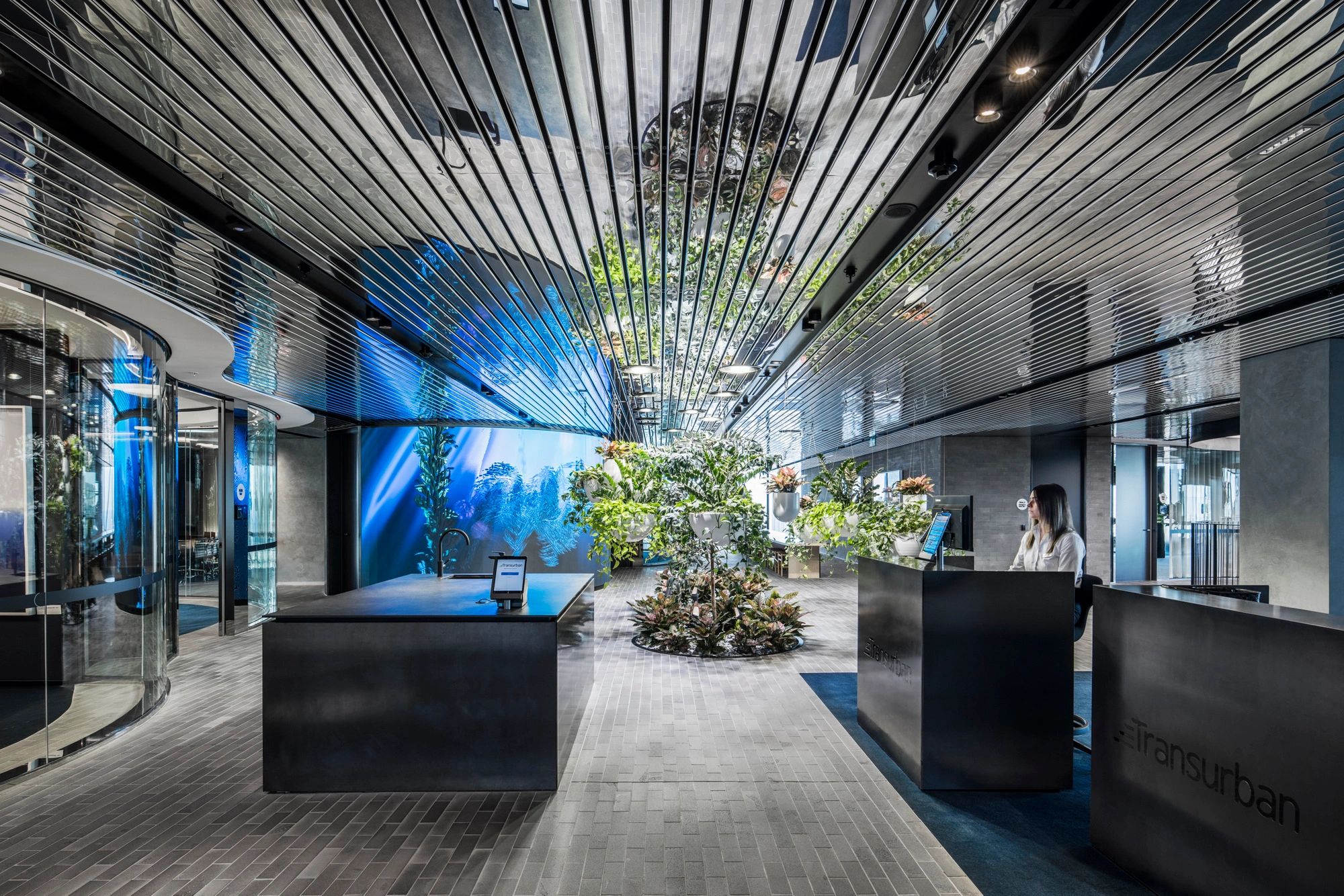 Modern office lobby with reflective ceiling and plants.