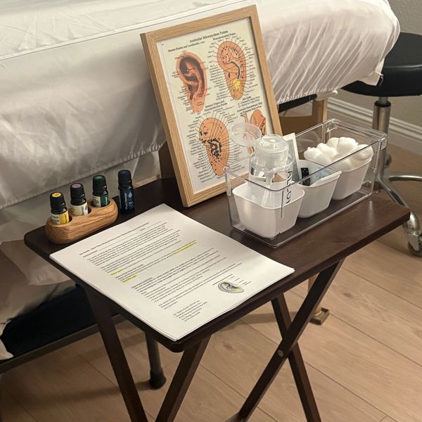 A therapy setup with essential oils, cotton swabs, and an ear acupuncture chart.
