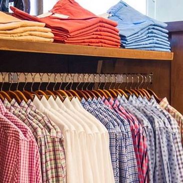 Neatly arranged men's shirts and folded pants in a clothing store.