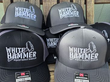 Collection of black and gray caps with 'White Hammer Equipment Repair' logo.