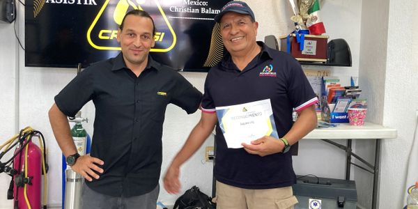 Two men smiling, one holds a certificate in an indoor setting.