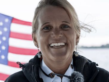 Smiling woman with American flag in the background.