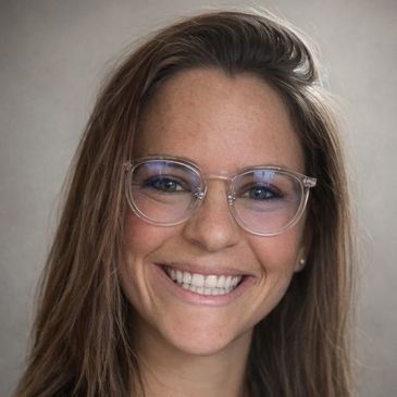 A young woman with clear glasses smiling warmly.